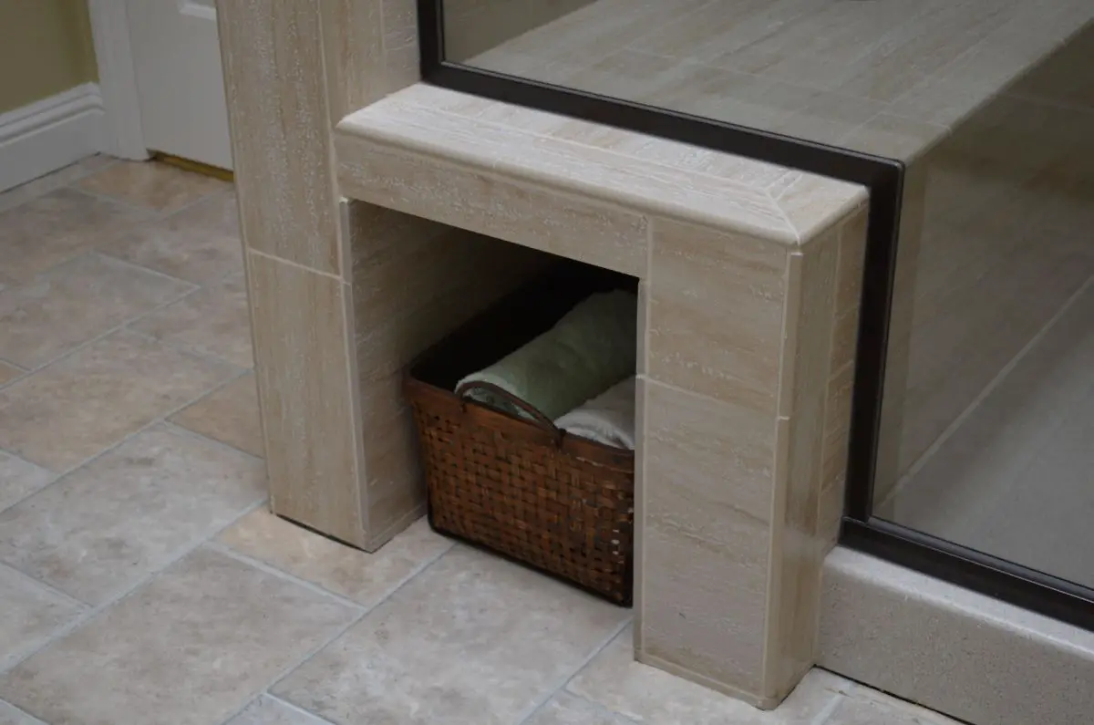 “Built-in bathroom niche with basket storage beneath tiled shower bench in remodel.”