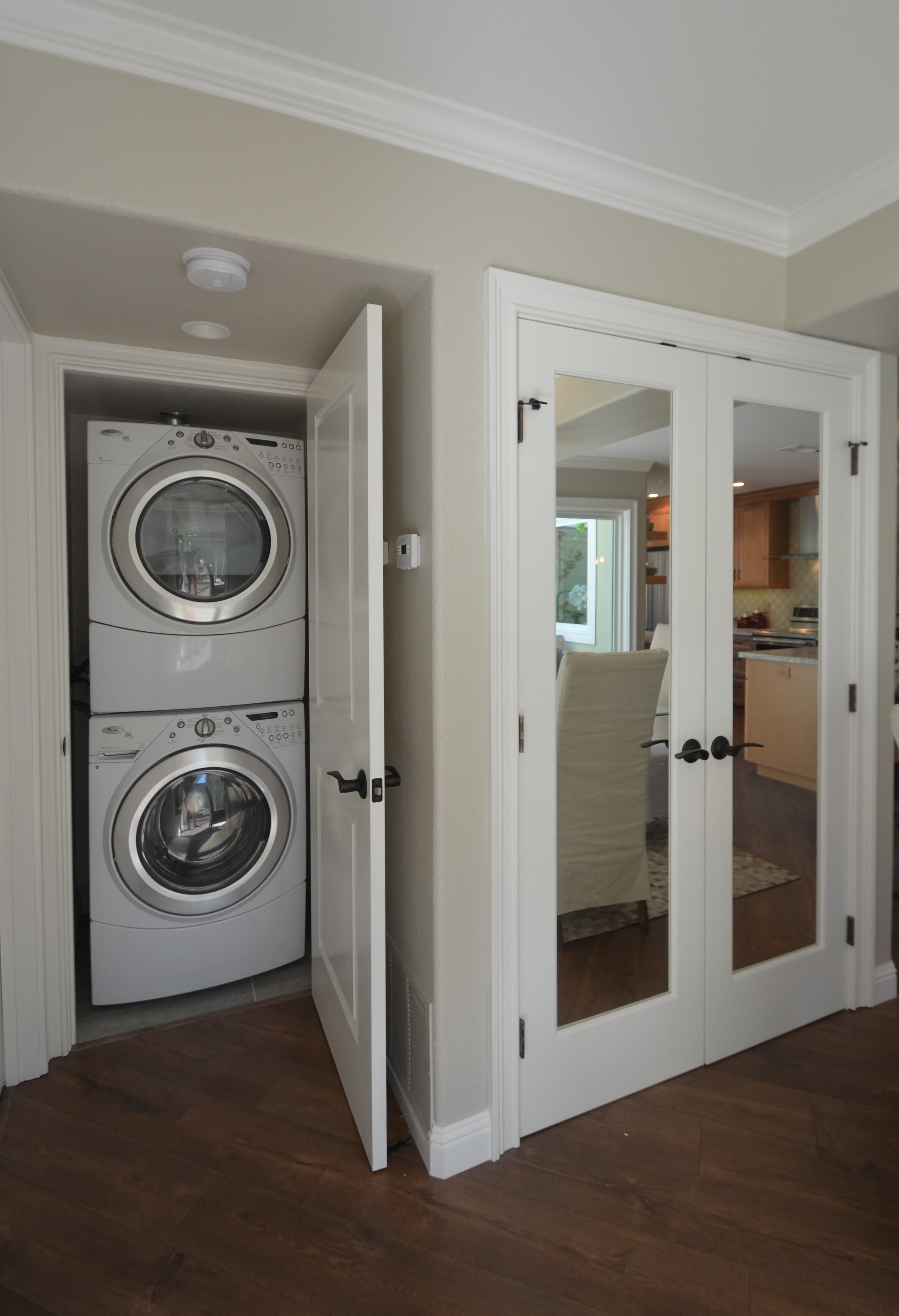 Stacked front-loading washer and dryer positioned inside a narrow hallway closet with a full swing door, showcasing a space-saving Rossmoor laundry nook designed to maximize vertical clearance and maintain a clean, unobtrusive look within the home.