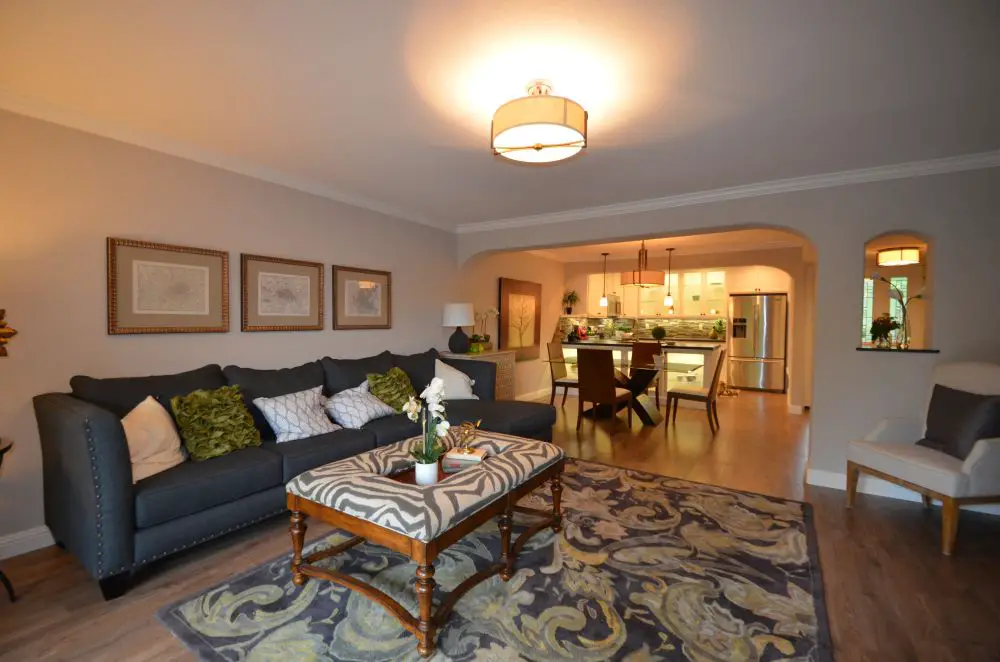 Open concept condo living room flowing into kitchen through wide opening, showing shared-wall friendly layout with defined spaces