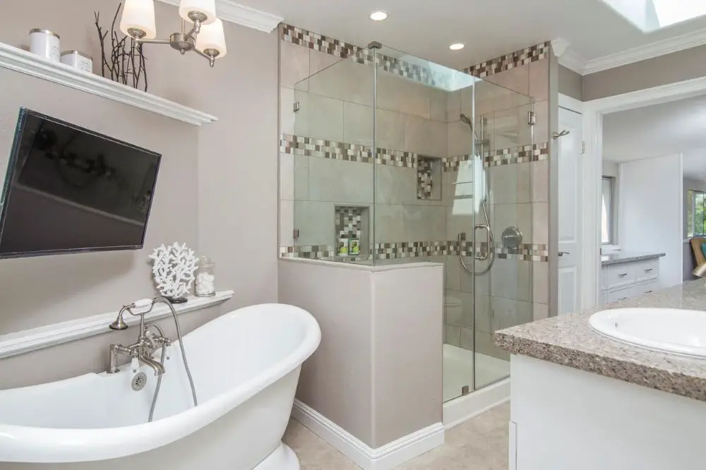 Smart bathroom with wall-mounted TV, freestanding tub, and glass shower combining modern technology and spa-like design