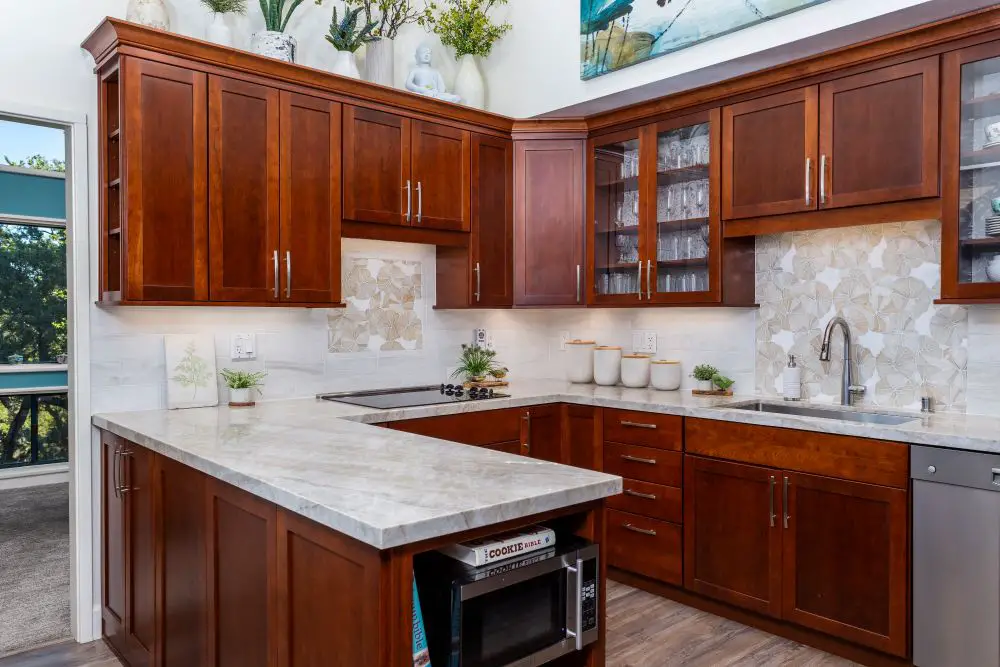Modern East Bay kitchen featuring rich cherry wood cabinets, quartz countertops, and a light floral backsplash — peninsula design by Toupin Construction for added prep and seating space.