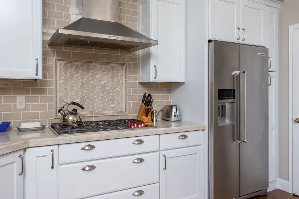 “Updated kitchen with white cabinetry, stainless appliances, and visible GFCI outlets near the backsplash showing proper electrical code compliance.”