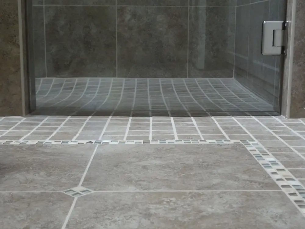 Curbless walk-in shower with slip-resistant tile flooring and frameless glass door — smooth transition for safe, barrier-free access.
