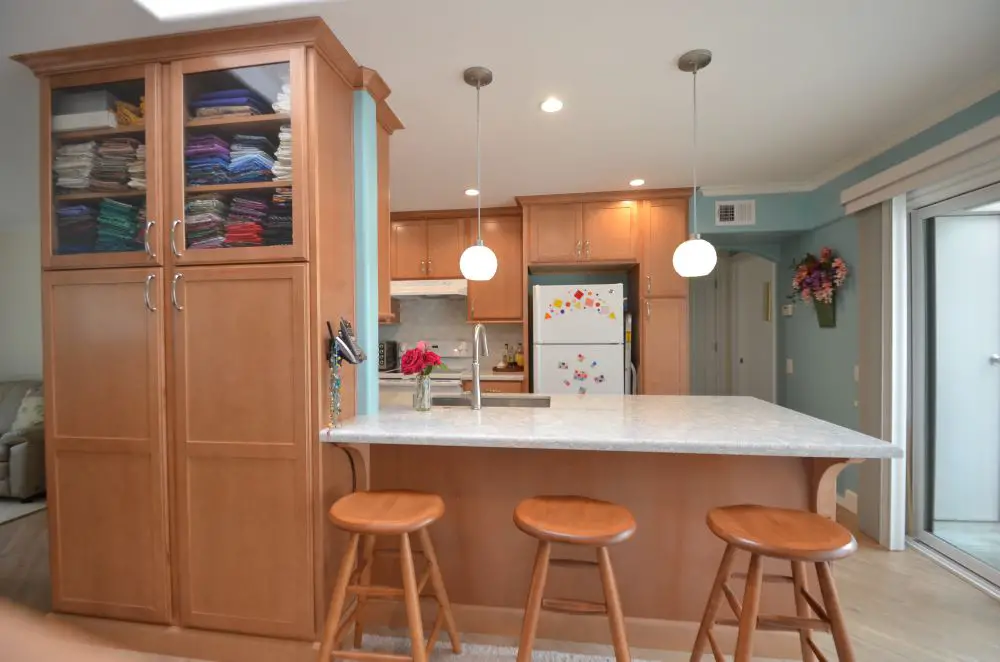 Open concept condo kitchen with peninsula seating and tall cabinetry replacing wall storage in HOA-regulated remodel