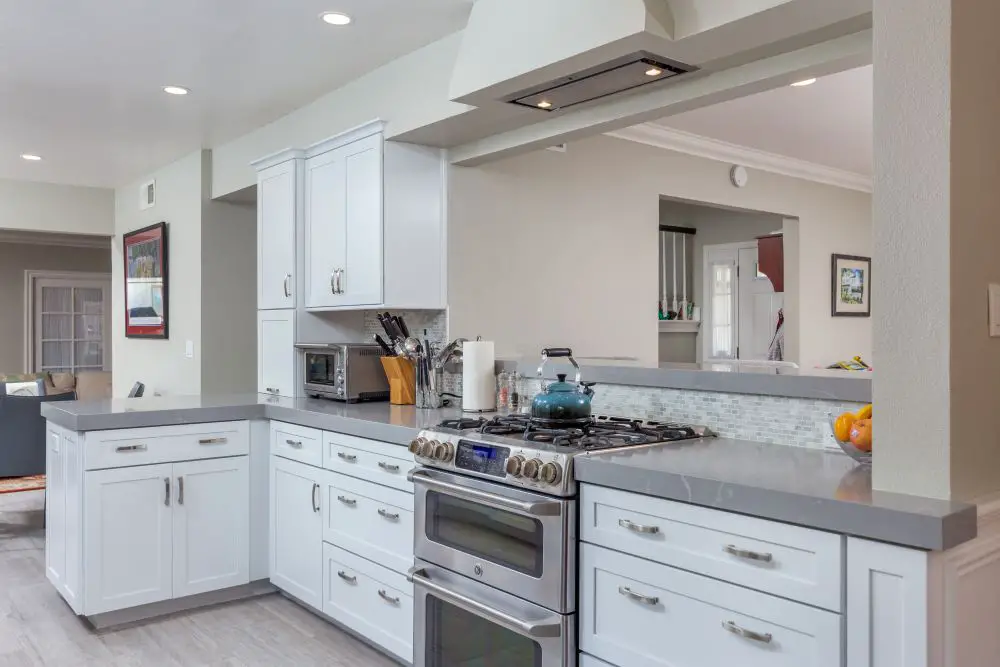 Modern open-concept kitchen remodel with white shaker cabinets, gray quartz countertops, and stainless steel range by Toupin Construction