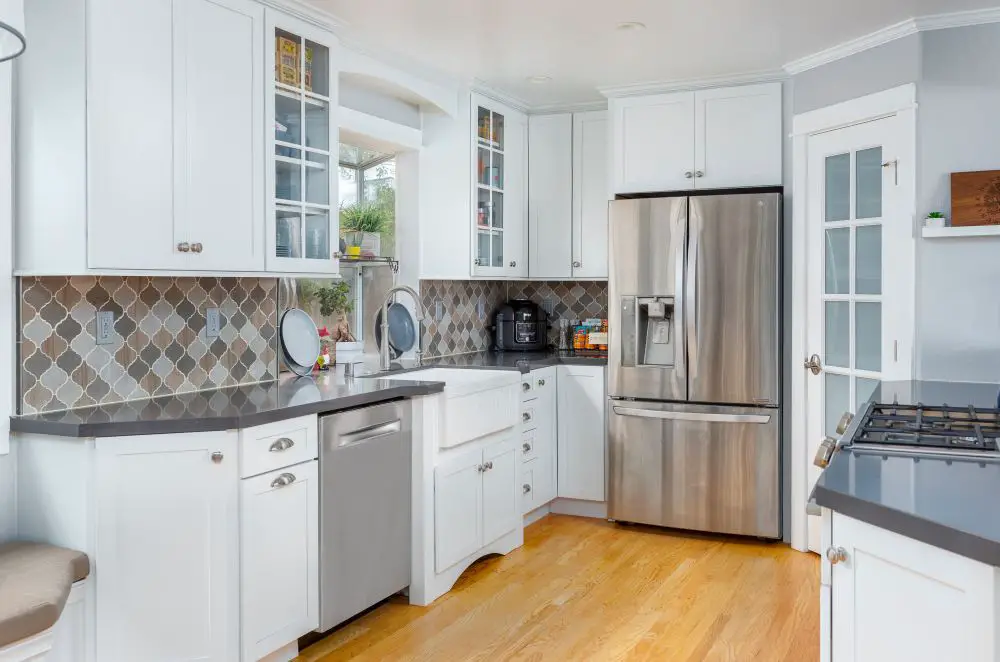 "Compact white kitchen with stainless steel appliances, farmhouse sink, and diamond-pattern backsplash showing efficient use of prep and cleaning zones."