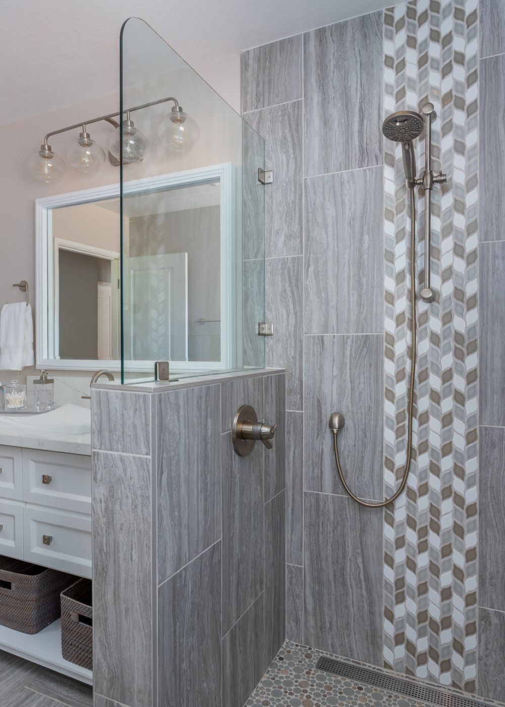 Modern walk-in shower with glass panel and gray tile accent wall.