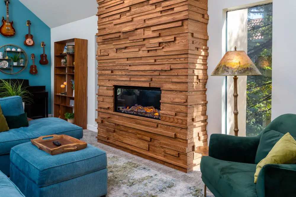 Custom living room remodel with vaulted ceilings, wood feature fireplace, teal accent wall, mounted guitars, and modern furnishings with natural light.