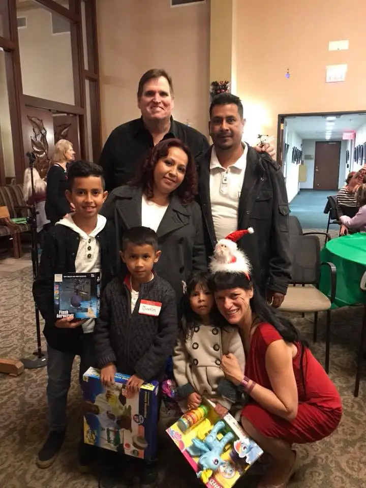 Tim Toupin posing with local families and children at a holiday community event.