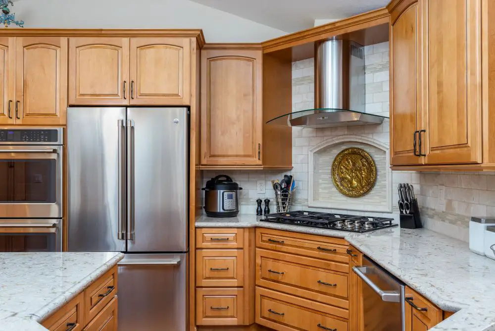 Alder wood kitchen cabinets with white quartz countertops, stainless steel appliances, and decorative range hood in a Walnut Creek kitchen remodel.