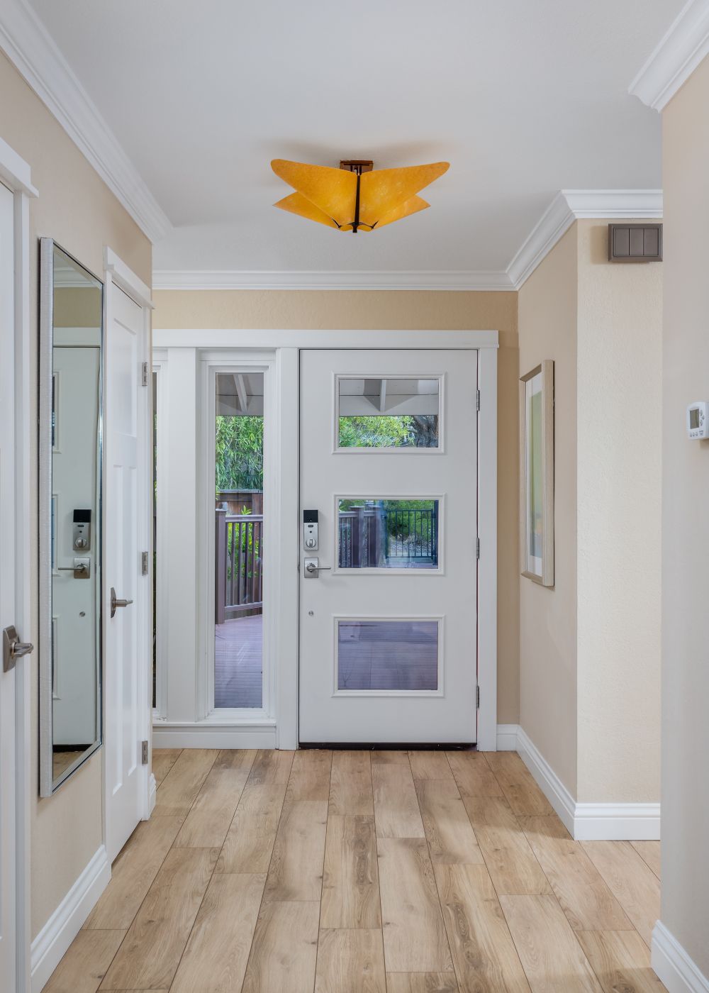 White front door with glass panels in a bright entryway with wood floors and neutral walls