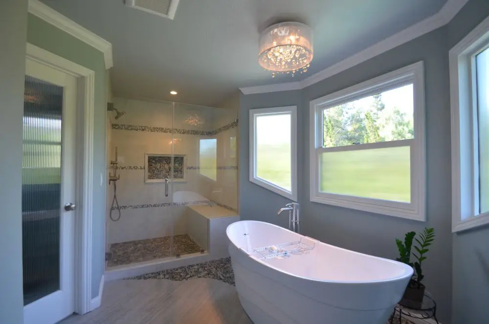 Ceiling chandelier above freestanding bathtub creating statement lighting in a bright bathroom