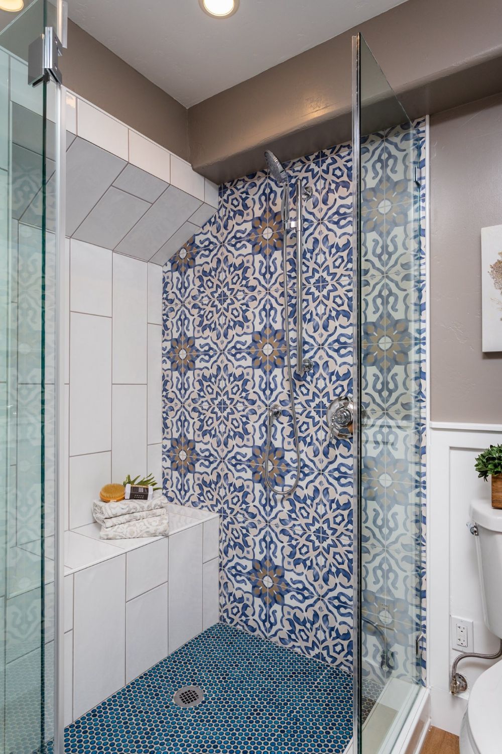 Walk-in shower with patterned tile feature wall, built-in bench, and frameless glass enclosure