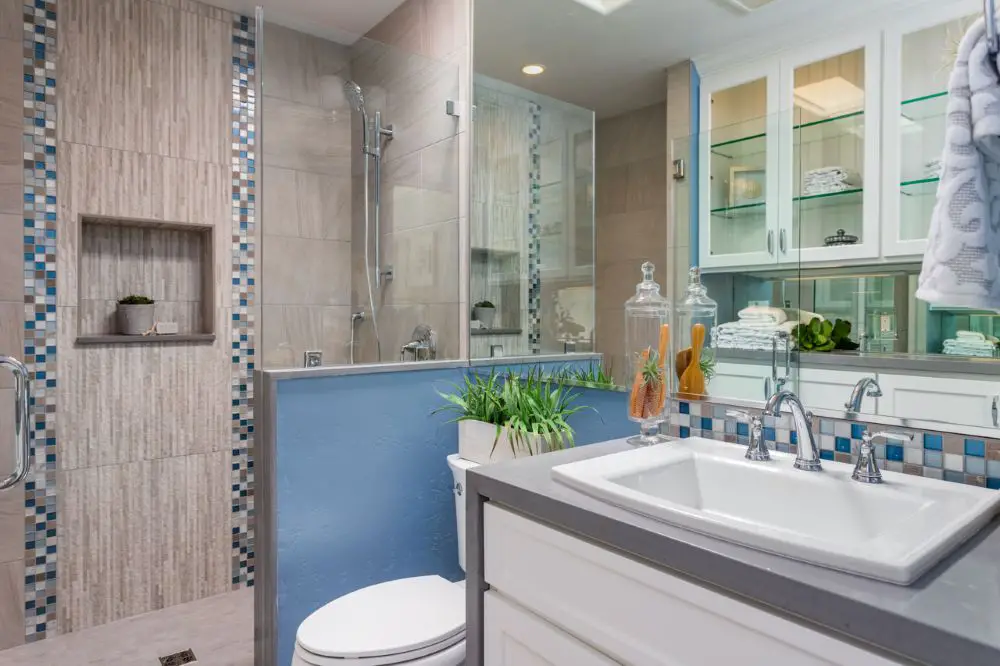 Bathroom with mixed tile accents, niche, and vertical mosaic border creating busy design