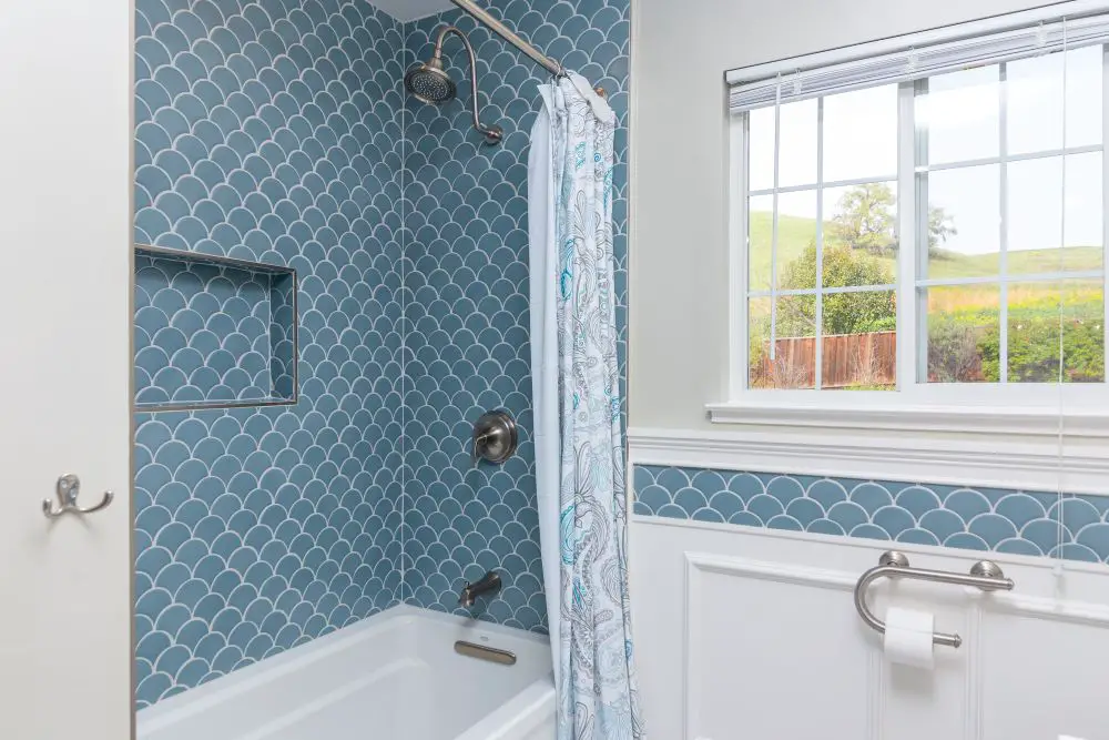 Bathtub shower with blue fish scale tile walls that dominate the space