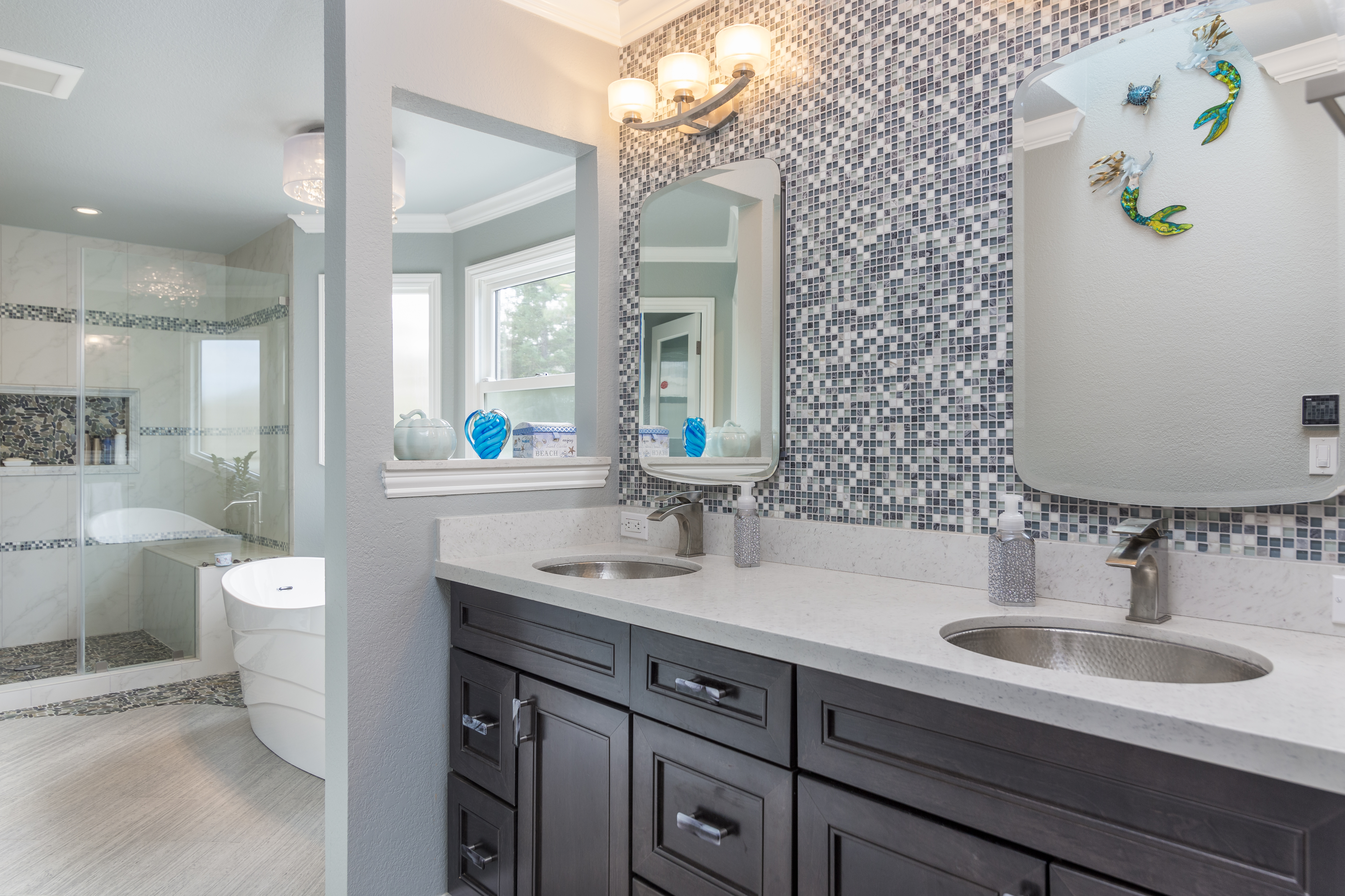 Bathroom with double mirrors, mosaic tile backsplash, and dark vanity cabinets