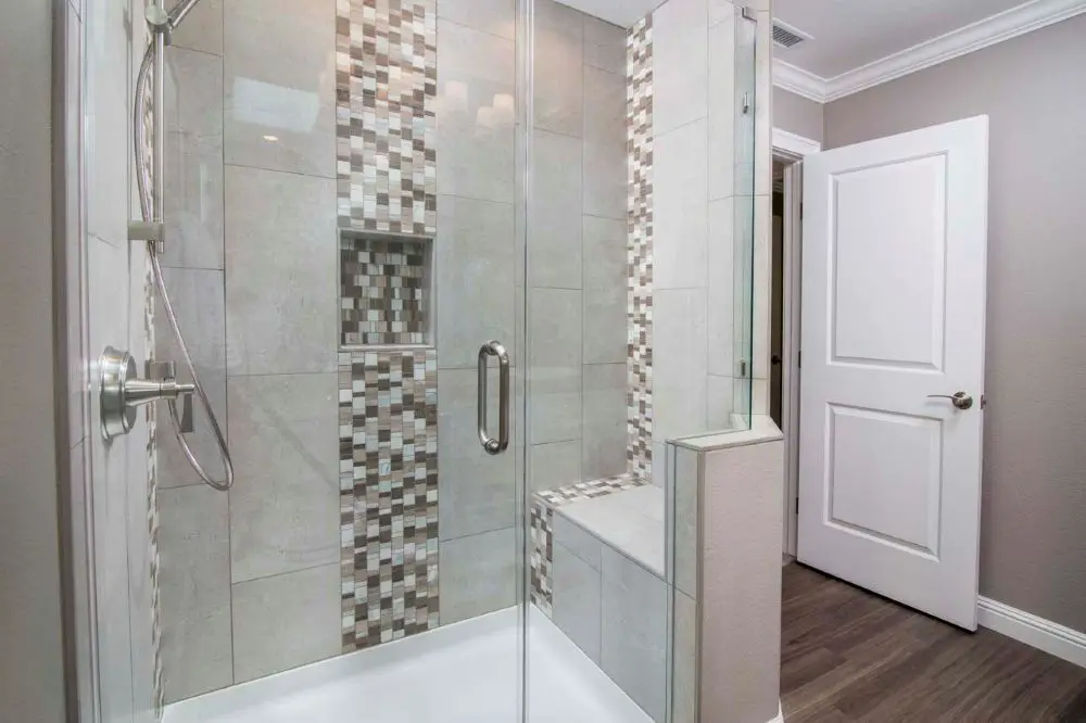 Custom walk-in shower with glass enclosure, mosaic accent tile, and built-in bench