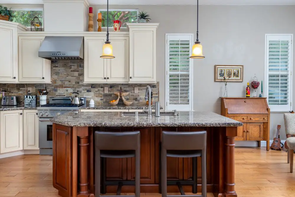 Granite kitchen island with seating, cream cabinets, and pendant lighting in open concept kitchen