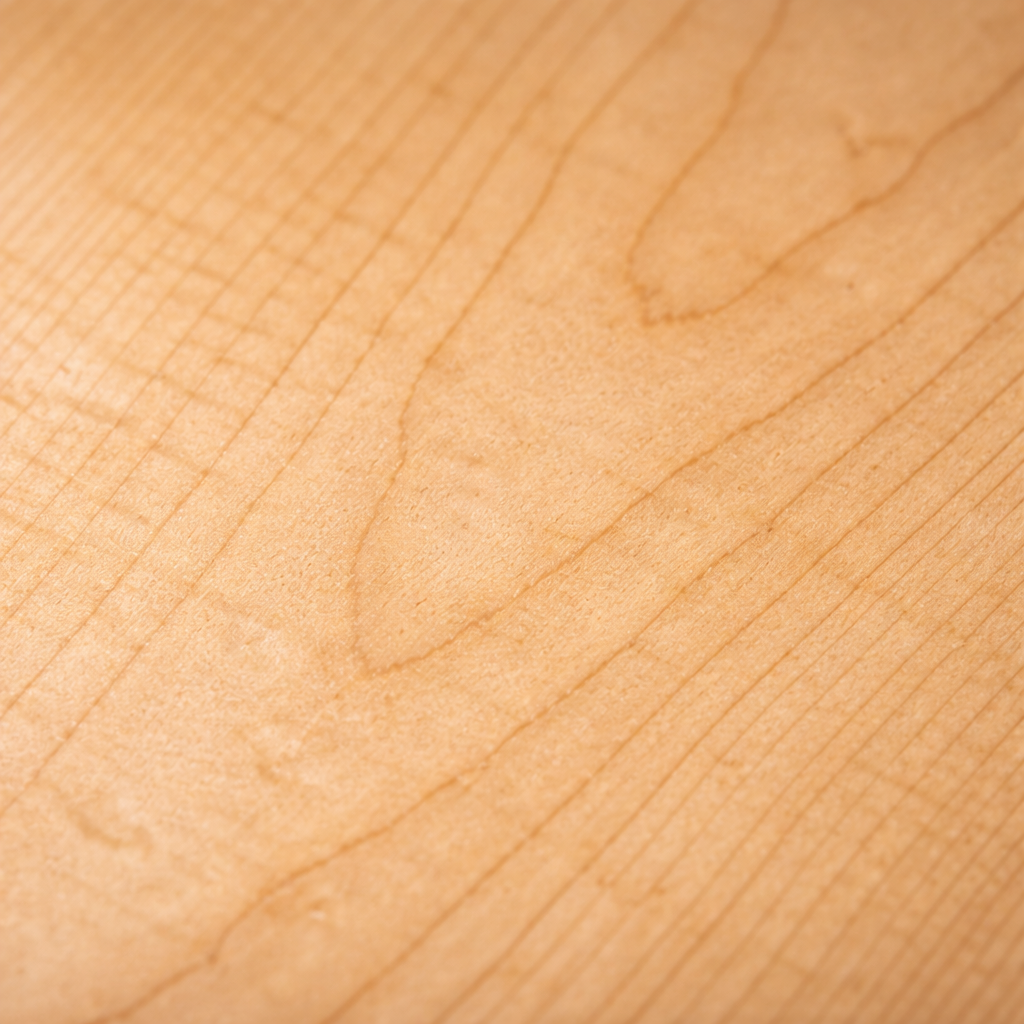 Close-up of maple wood grain with light blonde coloring and tight, subtle grain pattern, ideal for painted or modern cabinetry.
