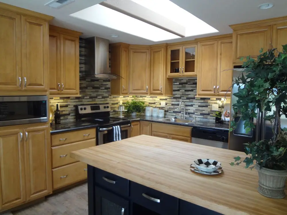 Butcher block kitchen island with light wood cabinets and skylight in bright traditional kitchen