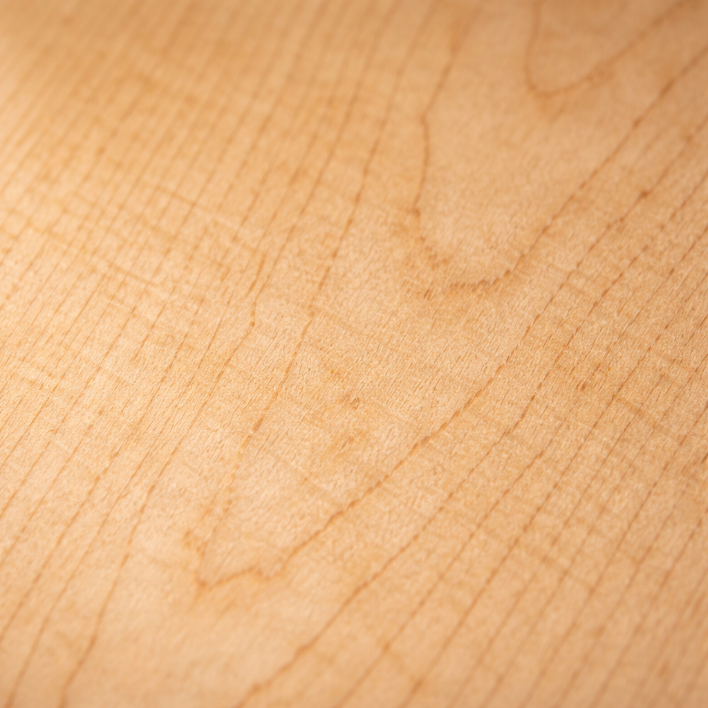 Close-up image of oak wood grain in a light honey tone, showing its distinctive linear texture and fine detail.
