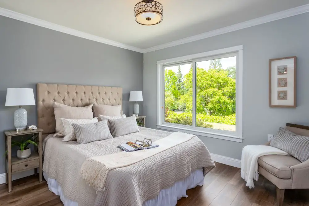 Bedroom with soft gray paint walls and large window showing paint color in bright daylight