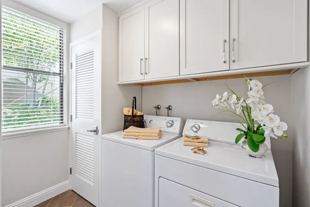 Stacked washer and dryer in bathroom Rossmoor Walnut Creek CA next to vanity compact condo laundry layout