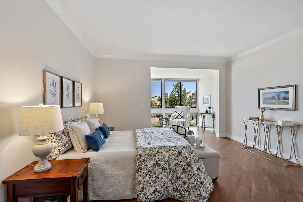Staged primary bedroom with neutral tones and wood floors