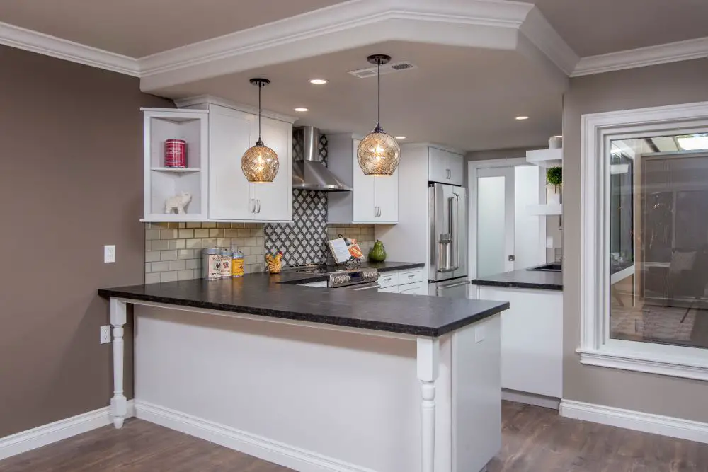 Dark quartz countertop peninsula with white cabinets in open concept kitchen