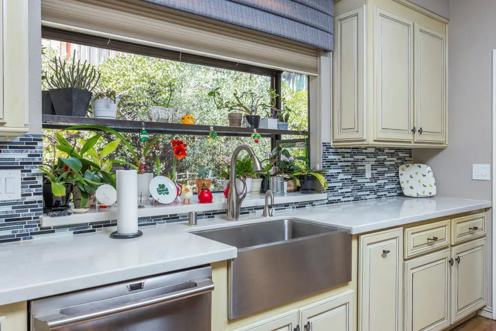 Rossmoor kitchen farmhouse sink with quartz counters and window filled with plants