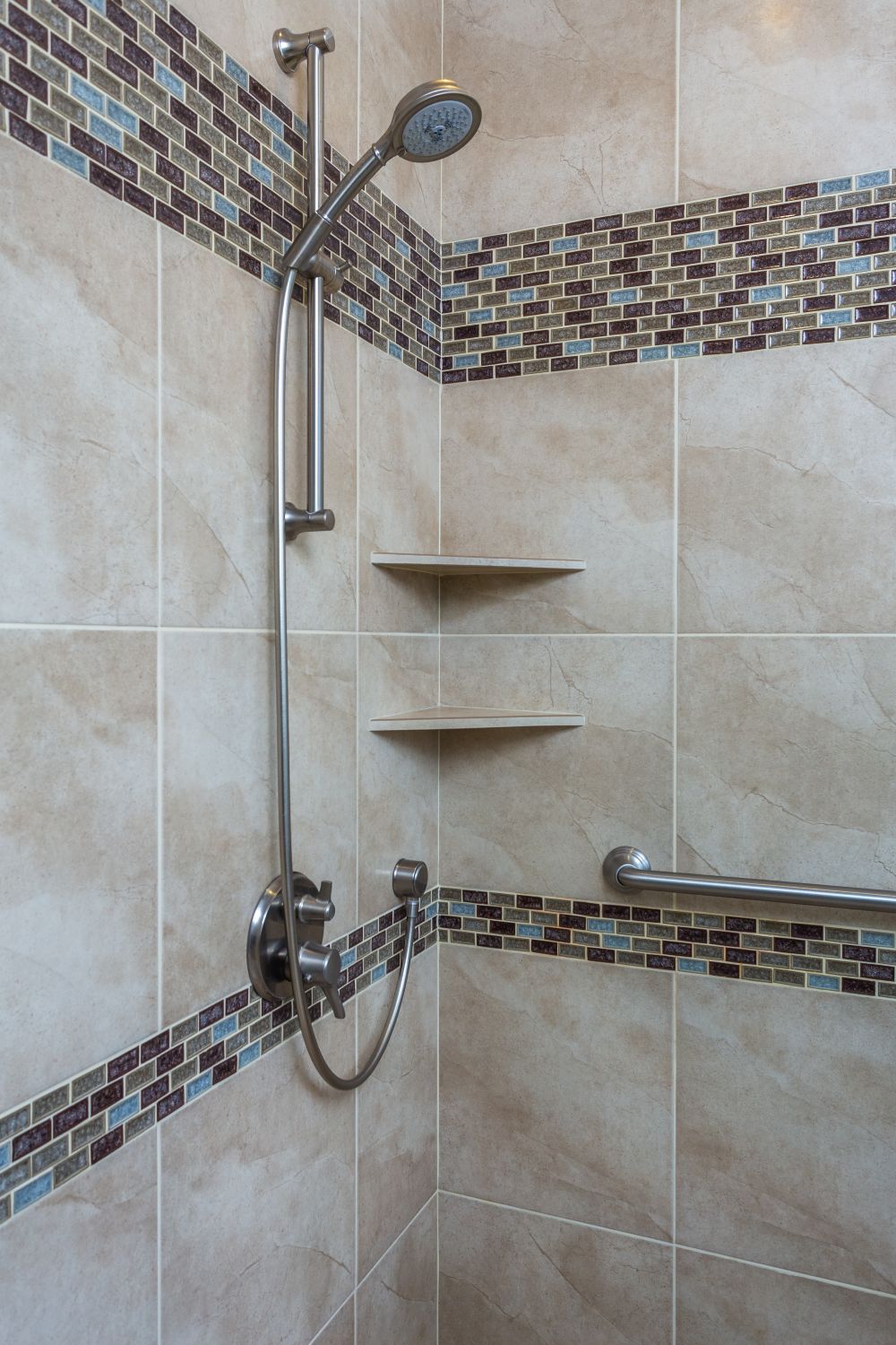 Shower with mosaic accent strip and corner shelves creating a busy tile layout