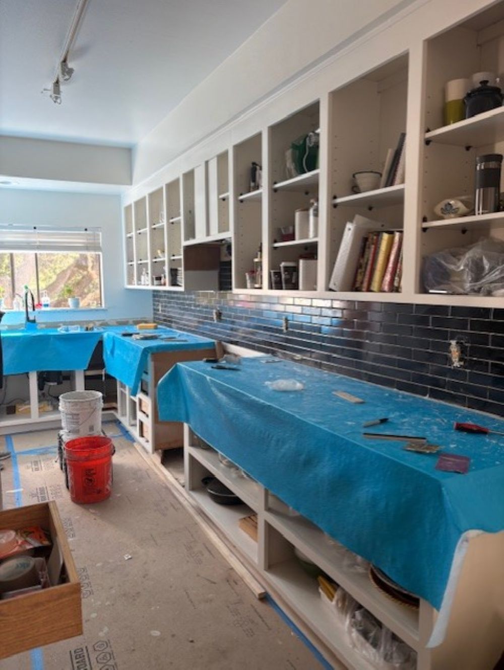 Kitchen in progress during cabinet refacing — doors removed, countertops covered, and backsplash tiling complete, Toupin Construction East Bay project.”