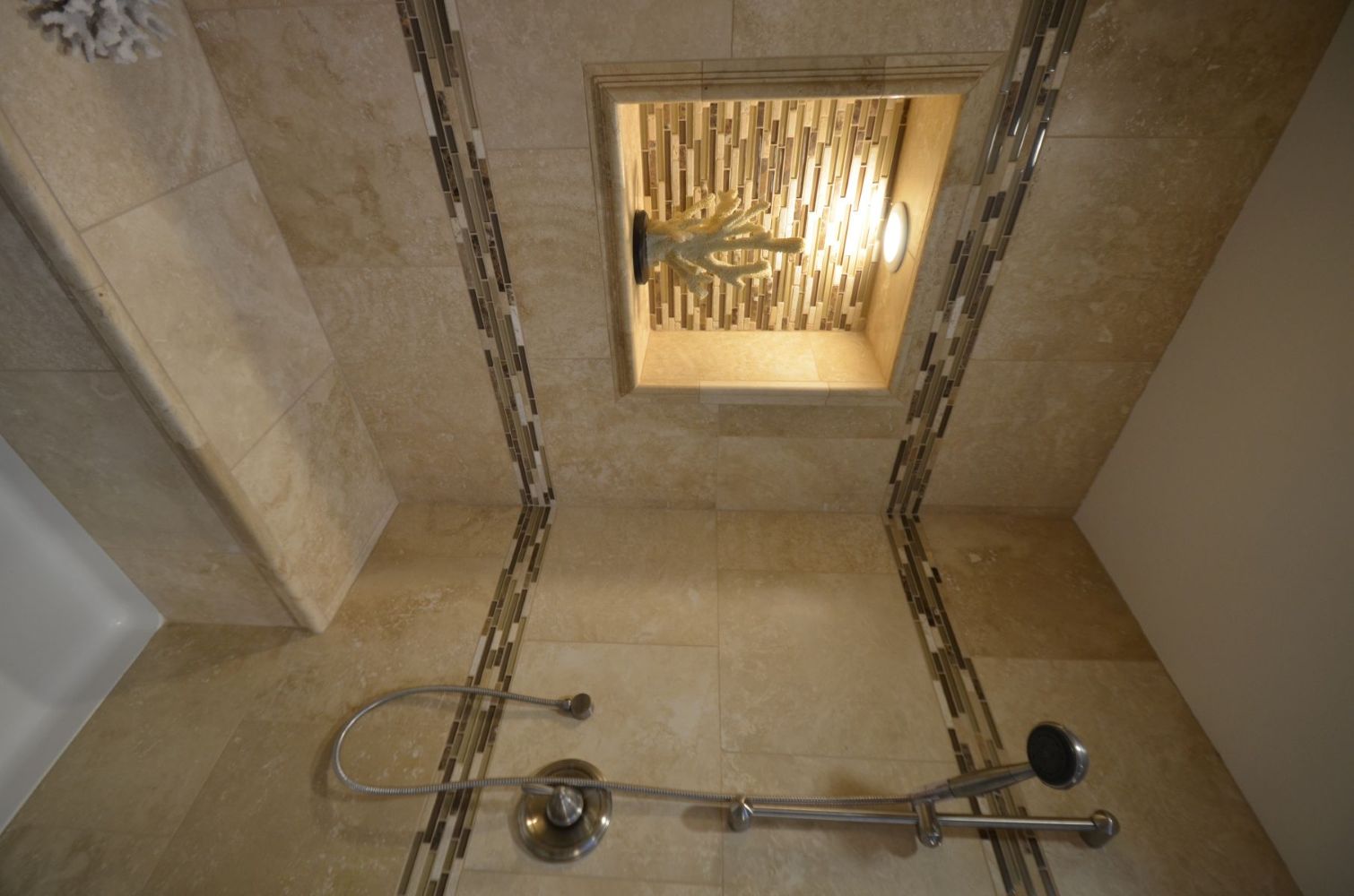 Walk-in shower with built-in bench, tiled niche, and handheld showerhead.