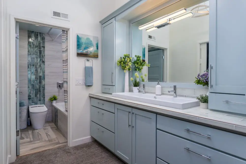 Bathroom remodel with double vanity blue cabinets large mirror and tiled shower in Walnut Creek
