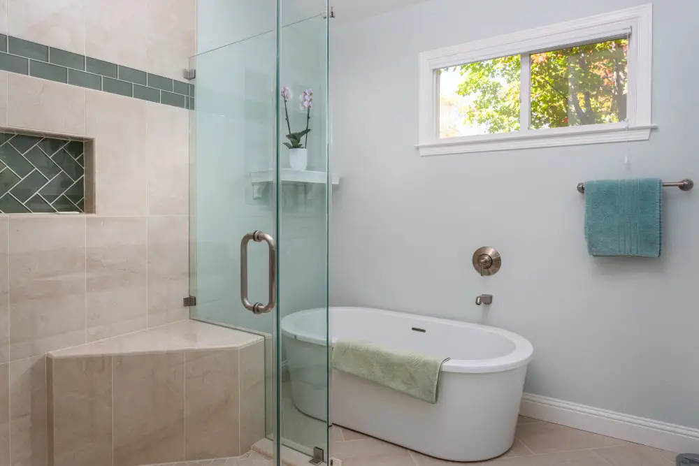 Bathroom with freestanding tub, glass shower, and natural light from window