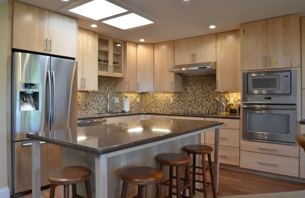 Kitchen with light wood cabinets, island seating, and skylights for natural light