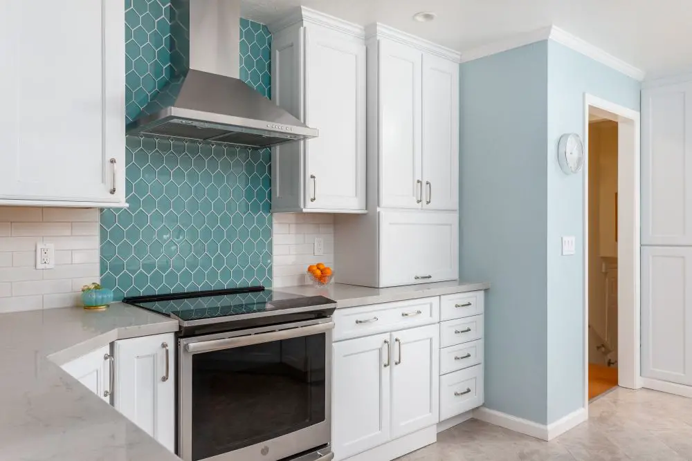 Teal hex tile kitchen backsplash with clean grout lines and white cabinets