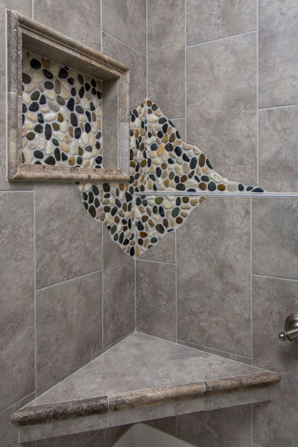 Pebble tile shower niche with multiple grout lines requiring maintenance and sealing