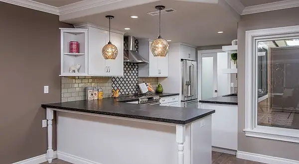 Open-concept white kitchen with peninsula seating and pendant lights in a Golden Rain remodel in Rossmoor. Golden Rain Whole-House Remodel | Rossmoor, Walnut Creek
