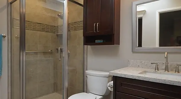 Updated Ptarmigan bathroom in Rossmoor featuring dark wood vanity, stone countertop, glass shower enclosure and modern lighting. 2648 Ptarmigan – Elegant Bathroom Remodel with Integrated Laundry