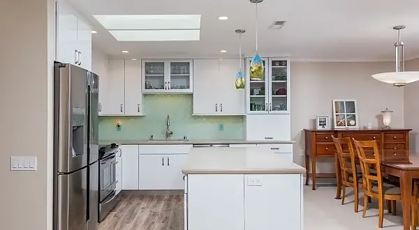 Although we wanted a modern sleek look, we also wanted the newly remodeled spaces in this home to have some soft touches too.  We went for a sort of beachy feel with our color tones.  Sandy tones along with touches of aqua and blue-green are featured here and there throughout the home.  The cabinets are a high gloss modern slab style.  Countertops a simple solid colored quartz with a fun glass mosaic tile backsplash with sandy grout to tie it in.  Slightly rustic looking LVT (luxury vinyl tile) flooring was also used, bringing in some contrast to the stark cabinetry.