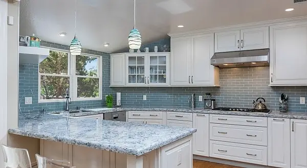 Bright white kitchen with large granite island and pendant lighting in a Creste Estates remodel in Alamo, California. Creste Estates Kitchen & Fireplace Remodel | Alamo