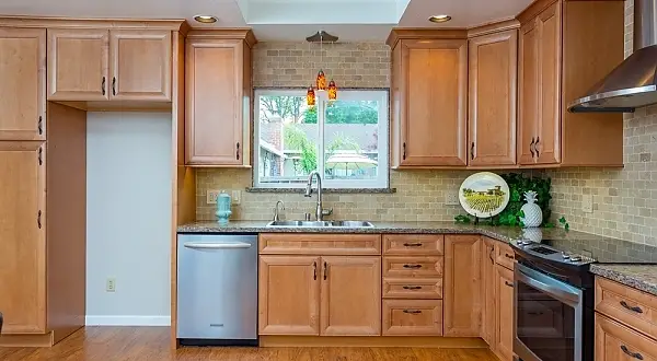 Remodeled Concord kitchen featuring warm maple shaker cabinets, granite countertops, stainless steel appliances, travertine tile backsplash, and recessed lighting. Concord Kitchen & Bathroom Remodel | Custom Cabinets & Accessible Shower