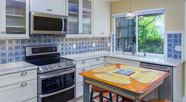 Sometimes inspiration for a space comes from a piece of art, or in this case a great piece of furniture like this client’s kitchen table. From that piece creams, golds and blues were utilized in the design to compliment it. The simplicity of the cream cabinets and fairly simple countertops allowed for a bold punch of fun color with the Mexican style backsplash tiles. In the bathroom we used rich red slate accents with a fairly neutral color scheme to give it a nice pop of color. The clients were also concerned with using green materials and thus glass recycled countertops were chosen for both spaces.