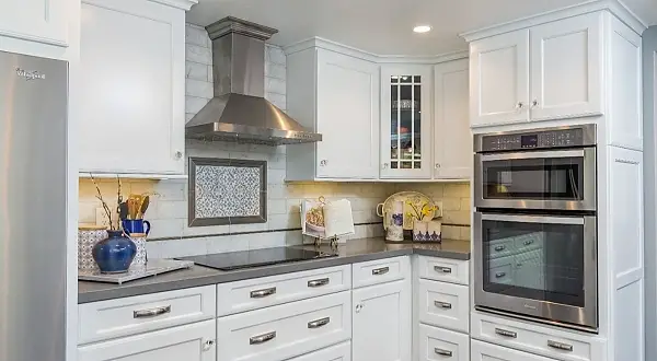 Remodeled kitchen with white cabinetry, stainless steel range hood, and built-in ovens in Rossmoor, Walnut Creek. Terra Granada Kitchen Remodel | Rossmoor, Walnut Creek